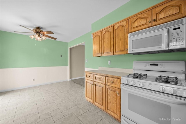 3700 Theodore St, Joliet, IL 60431 - kitchen with white appliances, a ceiling fan, light countertops, a wainscoted wall, and brown cabinets
