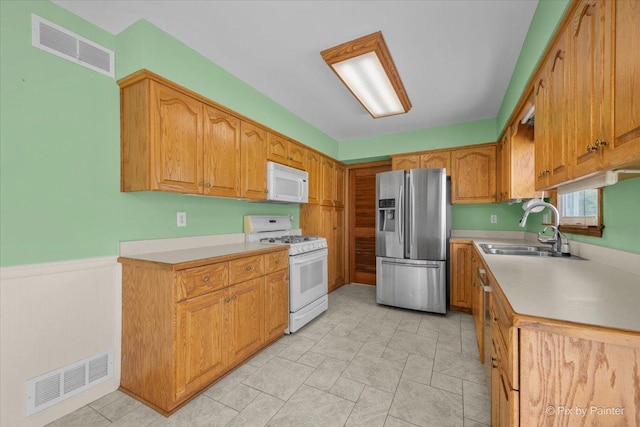 3700 Theodore St, Joliet, IL 60431 - kitchen featuring white appliances, a sink, light countertops, wainscoting, and brown cabinetry