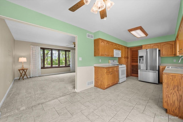 3700 Theodore St, Joliet, IL 60431 - kitchen with white appliances, ceiling fan, a sink, light countertops, and light carpet