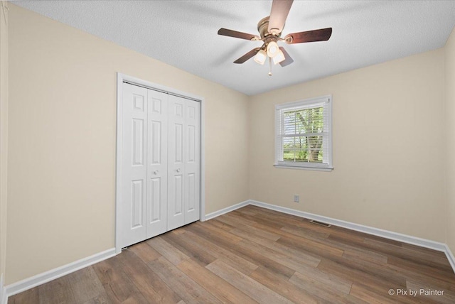 3700 Theodore St, Joliet, IL 60431 - unfurnished bedroom with wood finished floors, baseboards, a closet, ceiling fan, and a textured ceiling