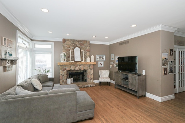living room featuring wood finished floors, baseboards, crown molding, a fireplace, and recessed lighting