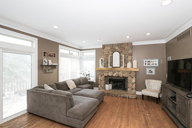 living area featuring ornamental molding, wood finished floors, healthy amount of natural light, a fireplace, and recessed lighting