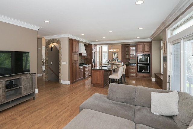 living room with a chandelier, baseboards, light wood-style flooring, recessed lighting, and ornamental molding