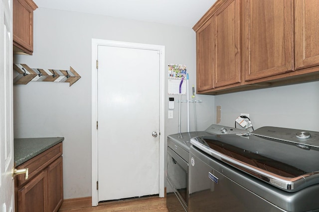 washroom featuring washer and dryer, light wood-style flooring, and cabinet space