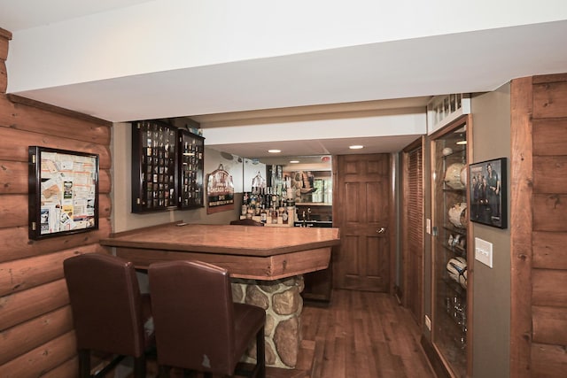 indoor dry bar featuring dark wood-style flooring and rustic walls