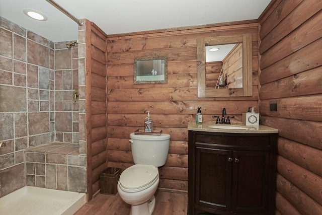 full bathroom with a stall shower, toilet, wood finished floors, vanity, and log walls
