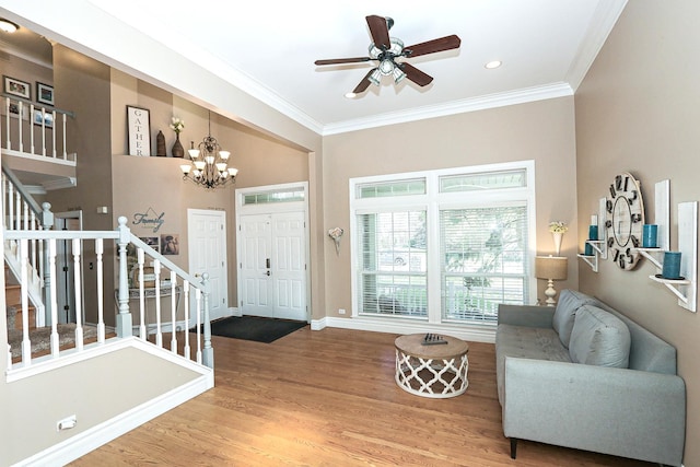 foyer featuring stairway, crown molding, wood finished floors, a chandelier, and ceiling fan