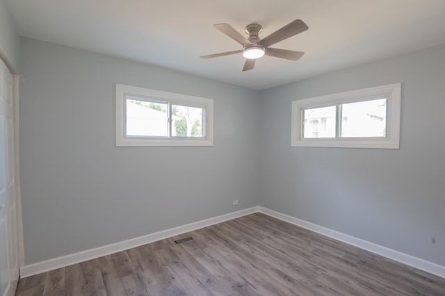 empty room with healthy amount of natural light, wood finished floors, and baseboards