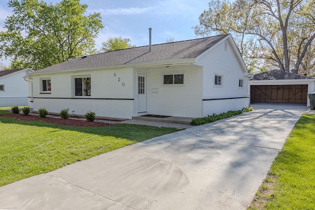 view of front of property with an outbuilding, a front lawn, concrete driveway, and a shingled roof