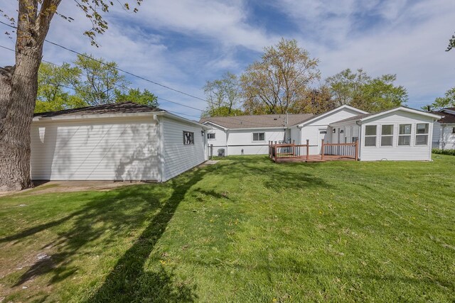 back of property featuring a yard, a wooden deck, and an outbuilding