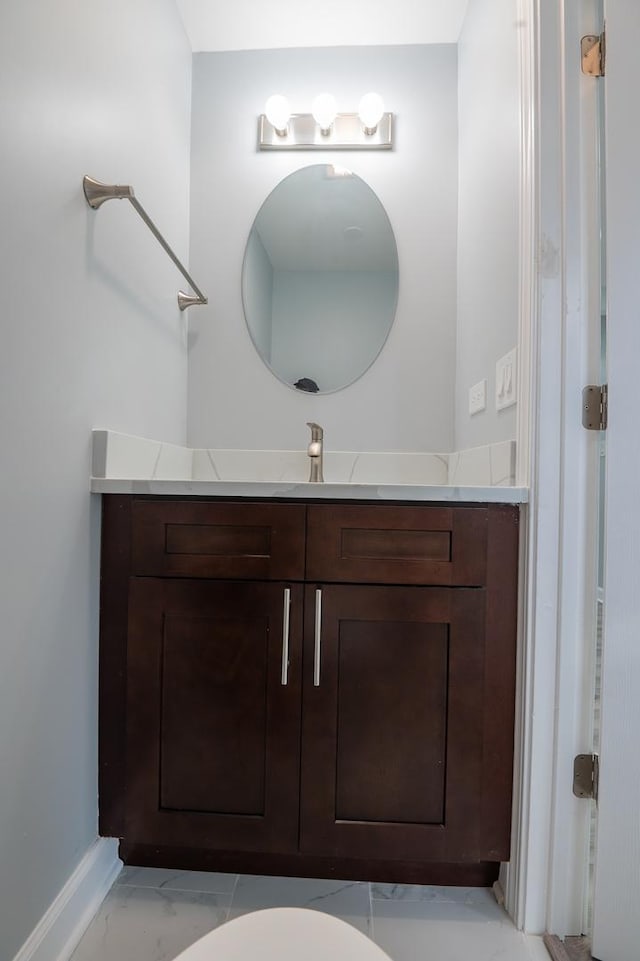 bathroom featuring marble look tile flooring, vanity, and baseboards