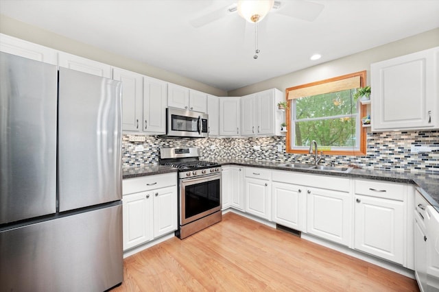 5157 Ribbon Ct, Monee, IL 60449 - kitchen featuring stainless steel appliances, a sink, light wood-style flooring, decorative backsplash, and white cabinets