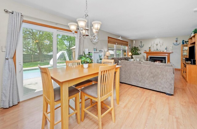 5157 Ribbon Ct, Monee, IL 60449 - dining area featuring light wood-style flooring, a chandelier, and a lit fireplace