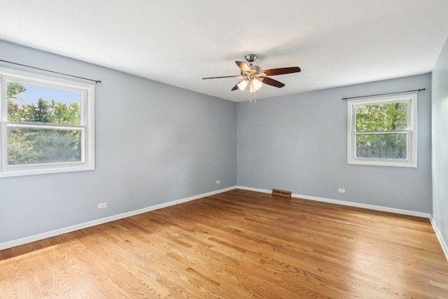 spare room featuring ceiling fan, baseboards, and light wood-style floors