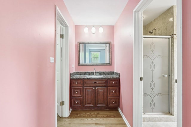 full bath featuring wood finished floors, a shower stall, and vanity