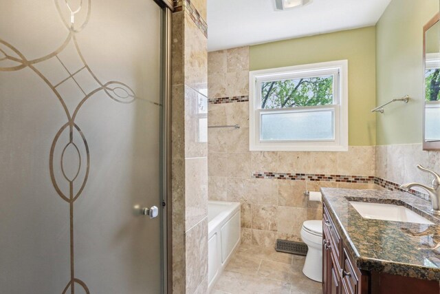 bathroom with a shower with door, healthy amount of natural light, toilet, vanity, and tile walls