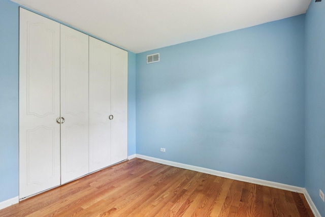 unfurnished bedroom with baseboards, light wood-type flooring, and a closet