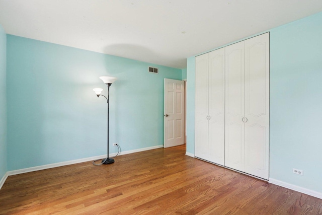unfurnished bedroom featuring light wood-type flooring, baseboards, and a closet