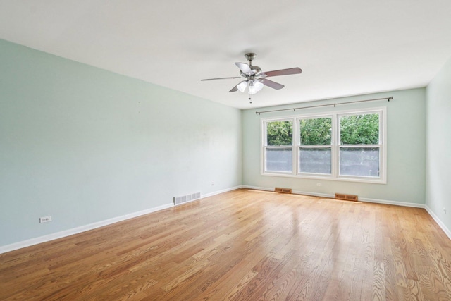 spare room with light wood-style floors, a ceiling fan, and baseboards