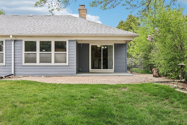 rear view of house with a chimney, a patio area, and a shingled roof