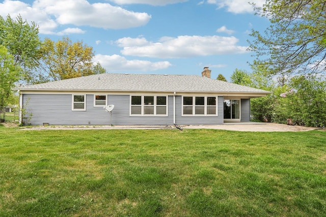 back of house featuring a patio area, a chimney, a lawn, and roof with shingles