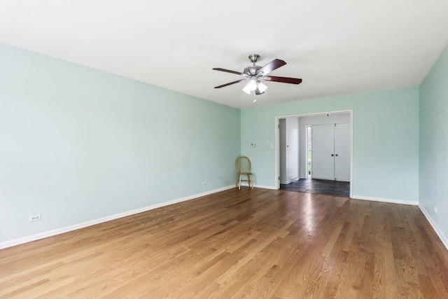 spare room with baseboards, wood finished floors, and a ceiling fan