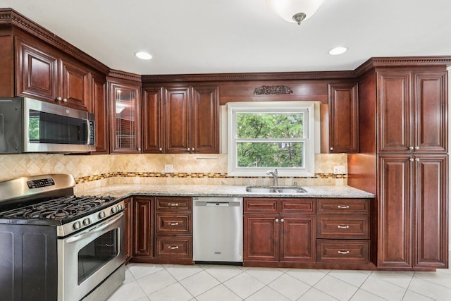 kitchen with appliances with stainless steel finishes, a sink, light stone countertops, backsplash, and recessed lighting
