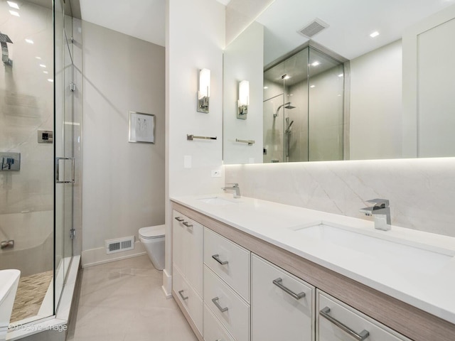 bathroom with a stall shower, toilet, double vanity, and baseboards