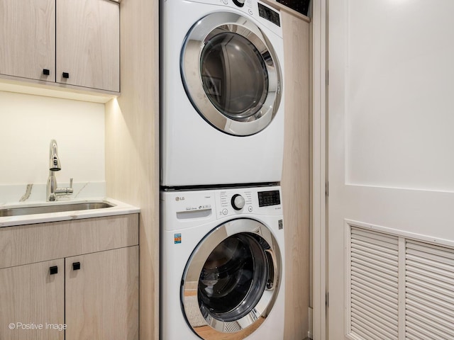 washroom with stacked washer and clothes dryer and cabinet space