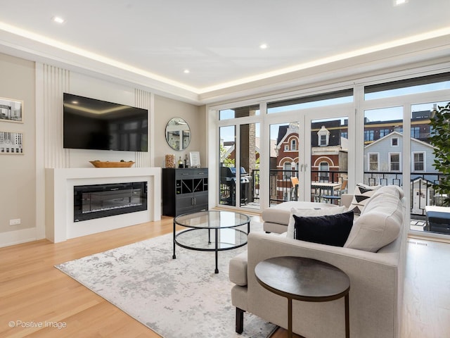 living room featuring wood finished floors, a glass covered fireplace, and recessed lighting
