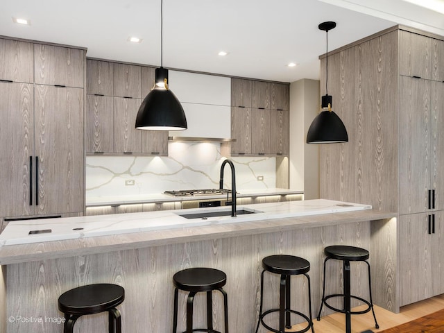 kitchen featuring light stone countertops, a kitchen breakfast bar, tasteful backsplash, modern cabinets, and recessed lighting