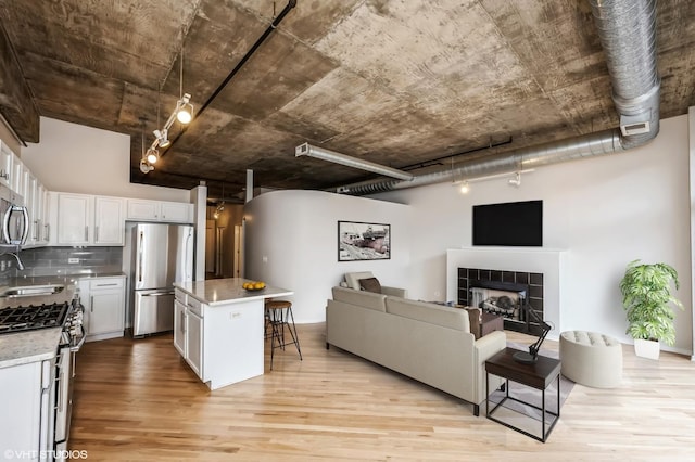 kitchen with appliances with stainless steel finishes, open floor plan, light wood-style flooring, a sink, and a breakfast bar area