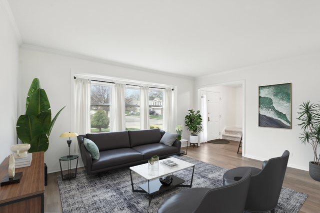 living area featuring wood finished floors, crown molding, and baseboards