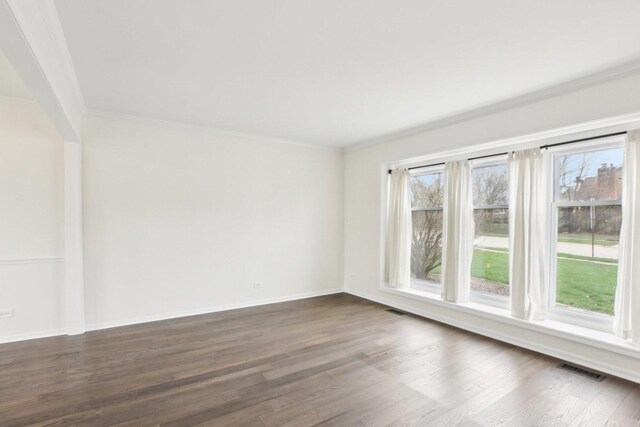 spare room featuring crown molding, dark wood-style floors, and baseboards