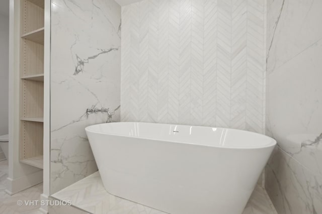 full bathroom featuring a freestanding bath and marble finish floors