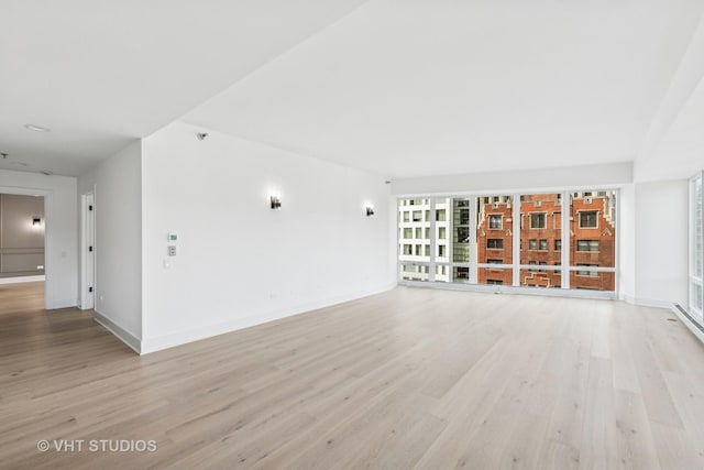 unfurnished living room with light wood finished floors and baseboards