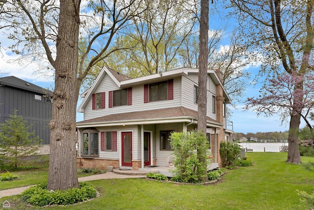 view of front of house featuring a front lawn, brick siding, a water view, and a chimney