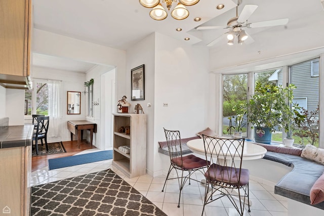 dining area featuring light tile patterned floors, a chandelier, ceiling fan, and baseboards