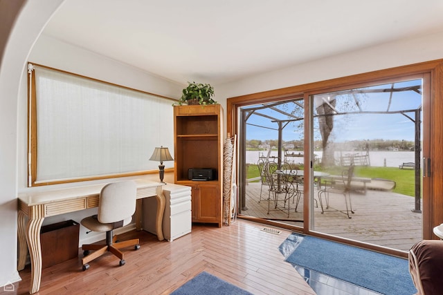 office space with a water view, light wood-style flooring, and arched walkways