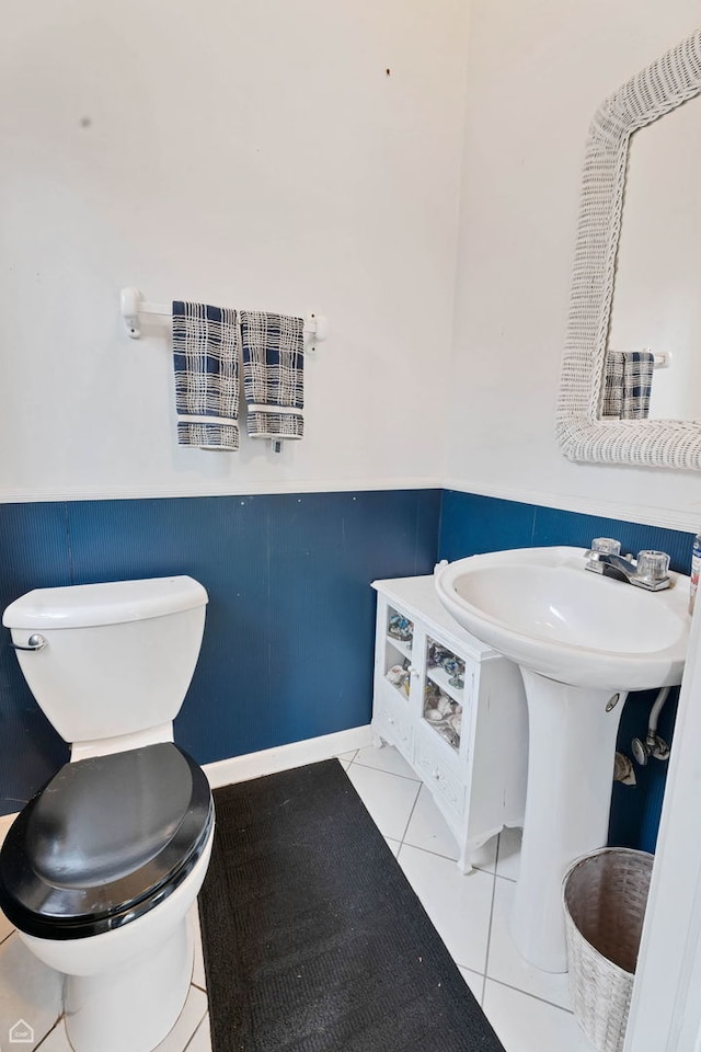 bathroom featuring tile patterned floors, a wainscoted wall, toilet, and a sink