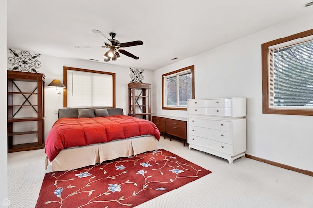 bedroom featuring light carpet, baseboards, and a ceiling fan