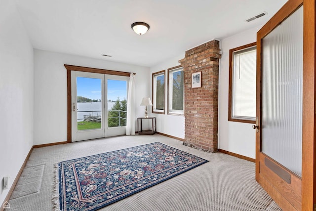 carpeted empty room with baseboards and a water view