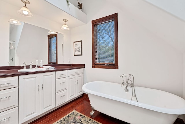 bathroom with double vanity, wood finished floors, a freestanding tub, and a shower with shower door