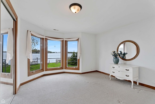 carpeted spare room with a water view and baseboards