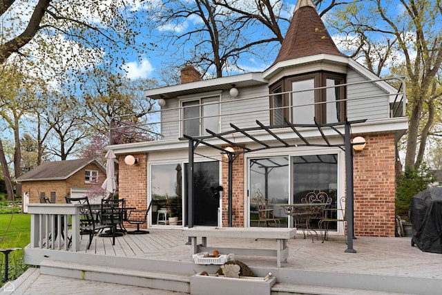 rear view of property featuring a wooden deck, brick siding, outdoor dining area, and a chimney