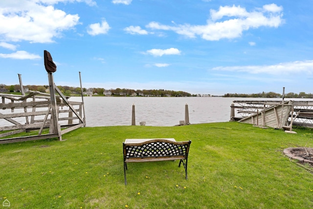 view of green lawn with a boat dock and a water view