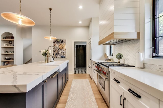 2312 W Hutchinson St, Chicago, IL 60618 - kitchen with high end stove, wall chimney range hood, a sink, a center island with sink, and decorative backsplash