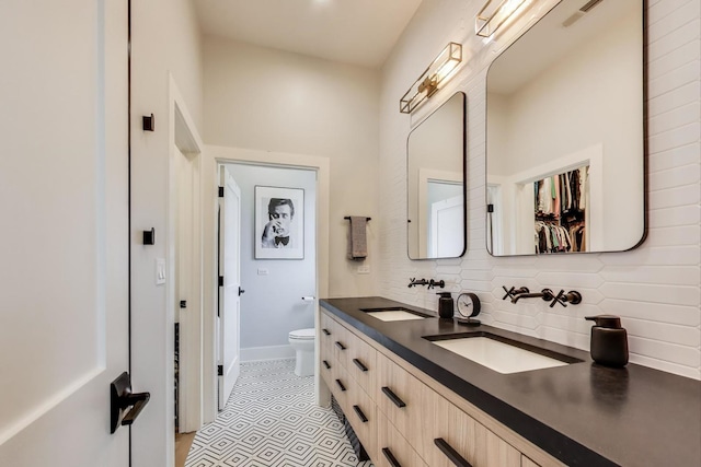 2312 W Hutchinson St, Chicago, IL 60618 - bathroom featuring toilet, double vanity, decorative backsplash, baseboards, and tile patterned flooring