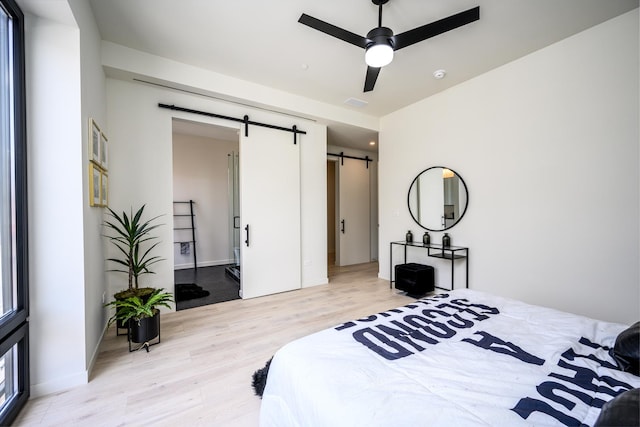 bedroom featuring a barn door and light wood-style floors