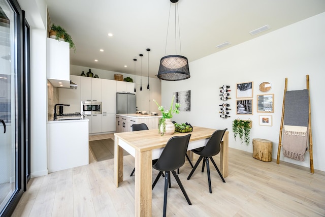 dining area with light wood-style floors and recessed lighting